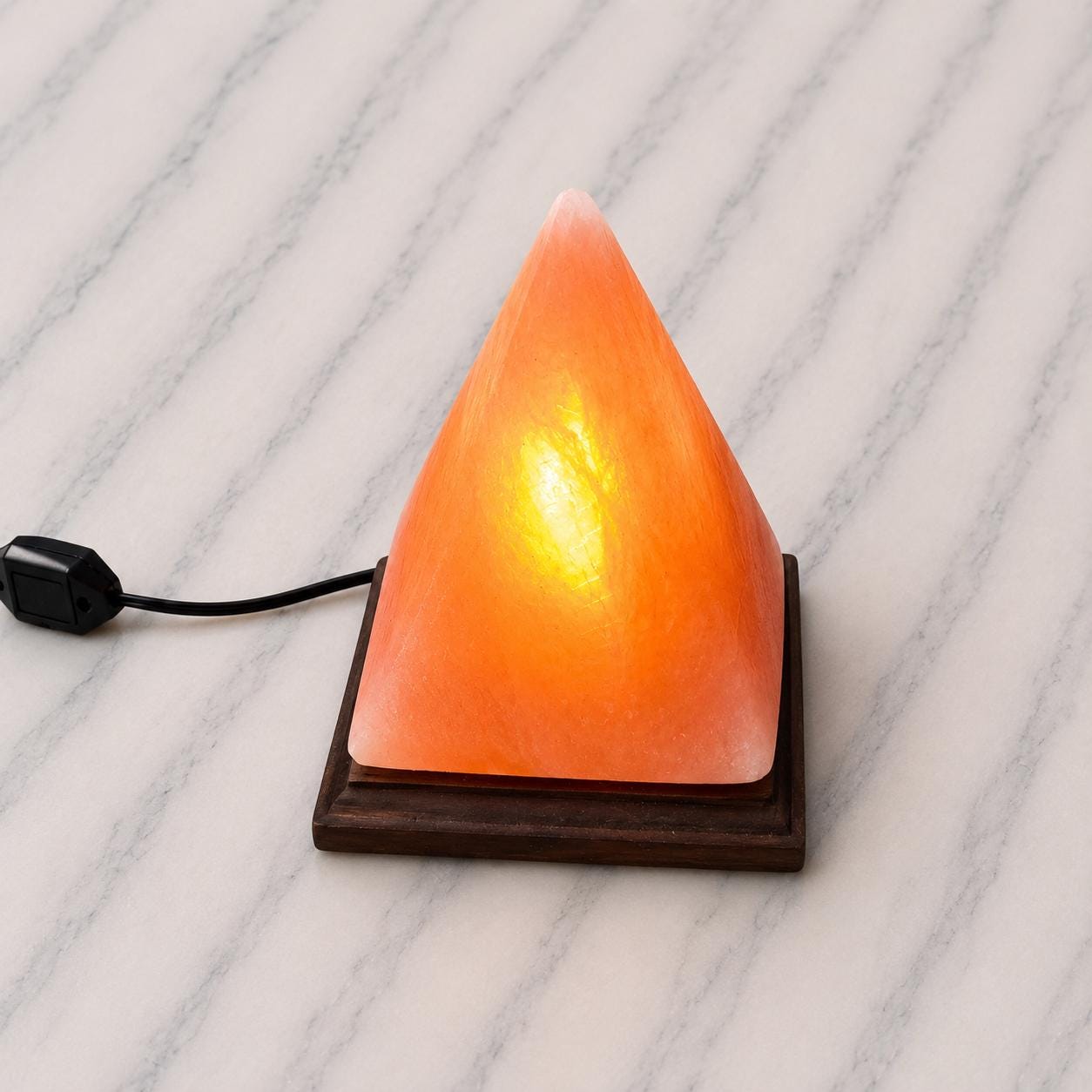 Pyramid Himalayan Salt Lamp glowing warm amber on a wood surface