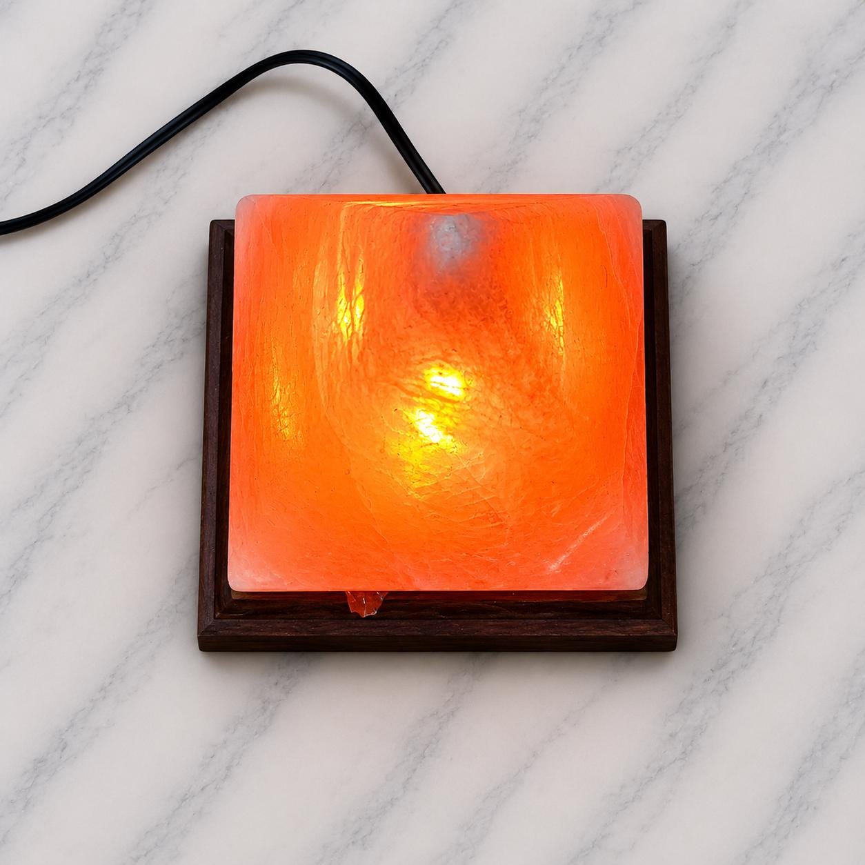 Pyramid Himalayan Salt Lamp glowing warm amber on a wood surface