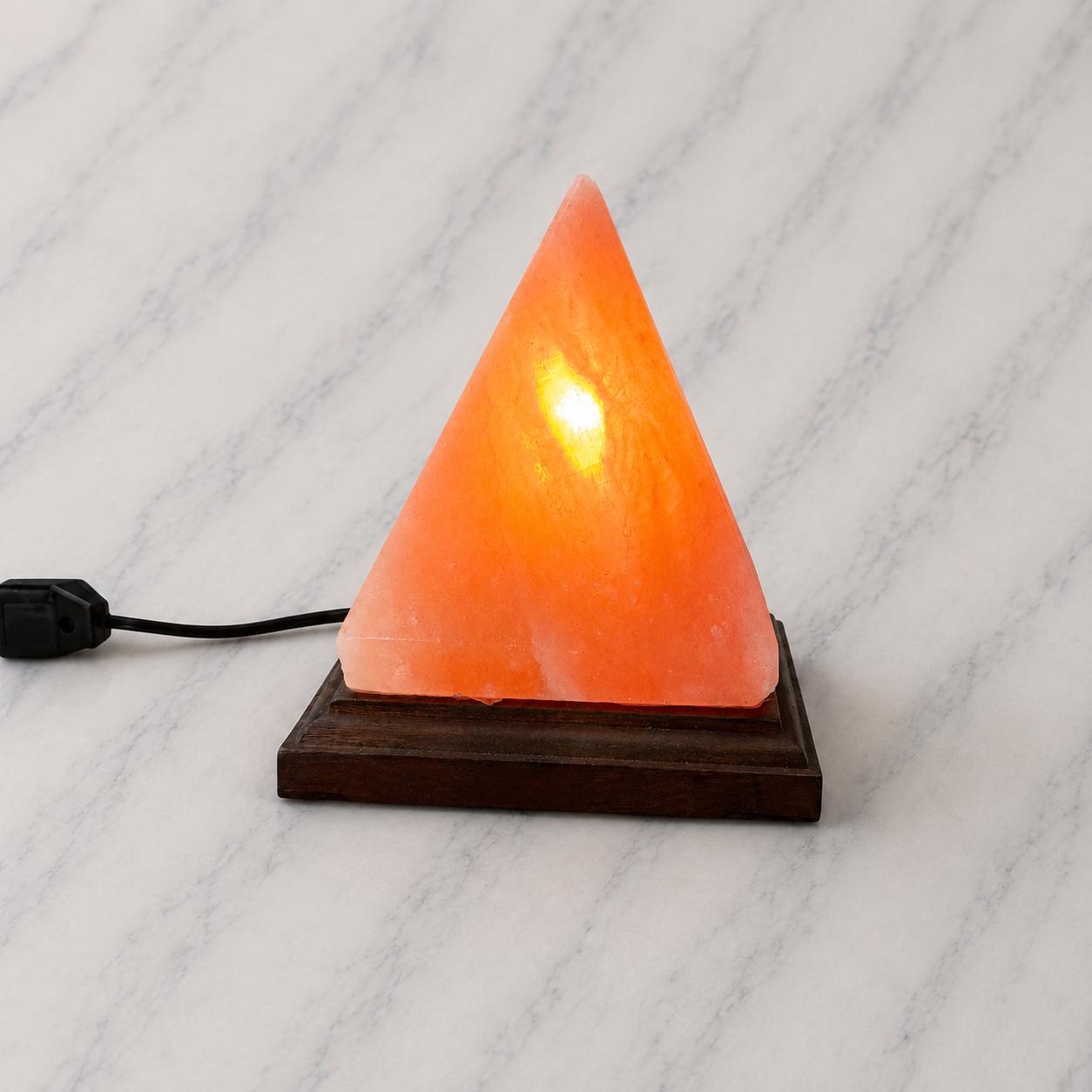 Pyramid Himalayan Salt Lamp glowing warm amber on a wood surface